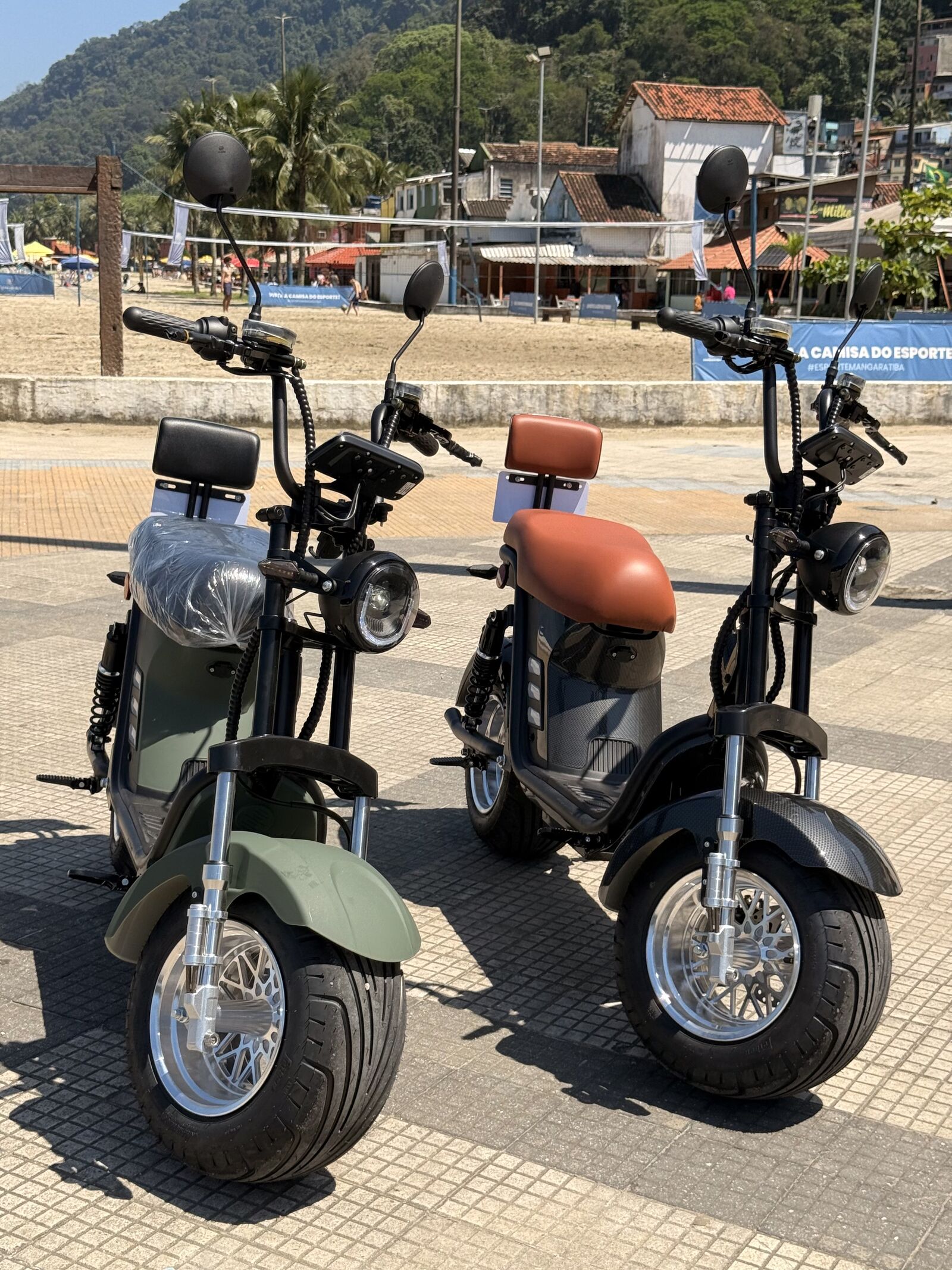 Duas scooters elétricas X13 verdes estacionadas na orla da praia